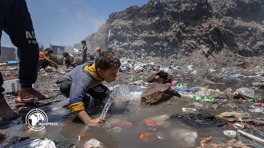 العطش يدفع طفلاً للشرب من مياه ملوثة وسط أكوام النفايات في غزة
